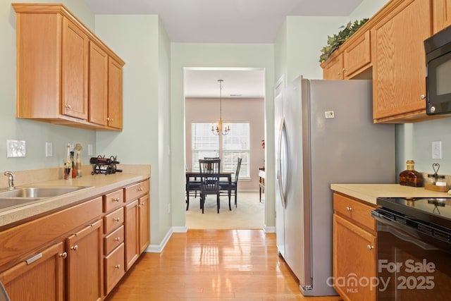 kitchen featuring a sink, an inviting chandelier, black appliances, and light countertops