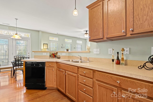 kitchen with a sink, black dishwasher, a peninsula, and light countertops