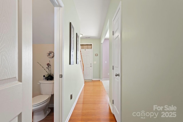 corridor featuring light wood finished floors and baseboards