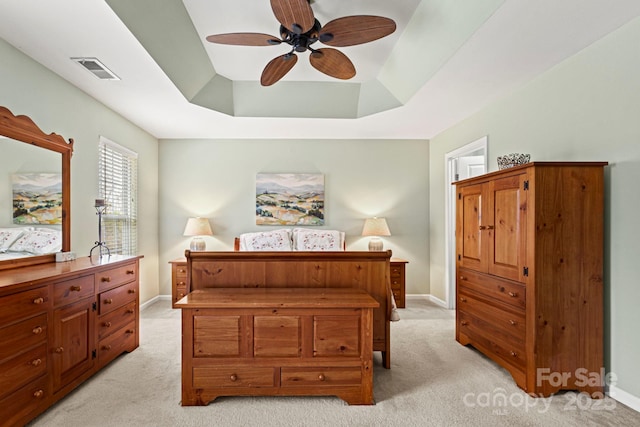 bedroom with a raised ceiling, baseboards, visible vents, and light carpet