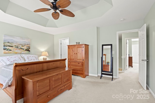 bedroom featuring baseboards, a raised ceiling, light carpet, and a ceiling fan