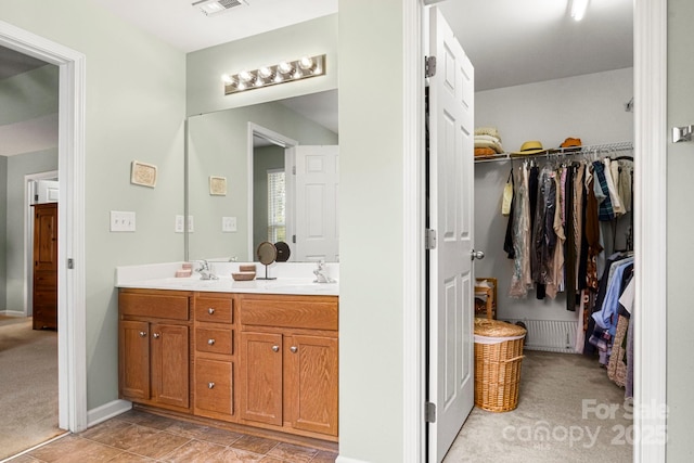 full bathroom with double vanity, a spacious closet, baseboards, and a sink