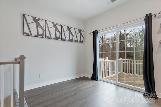 unfurnished room with visible vents, baseboards, and wood finished floors