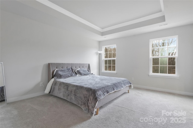 bedroom with a tray ceiling, multiple windows, carpet flooring, and visible vents