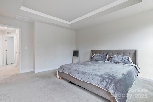 carpeted bedroom with visible vents, baseboards, and a tray ceiling