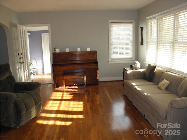 living room featuring arched walkways, baseboards, and wood finished floors