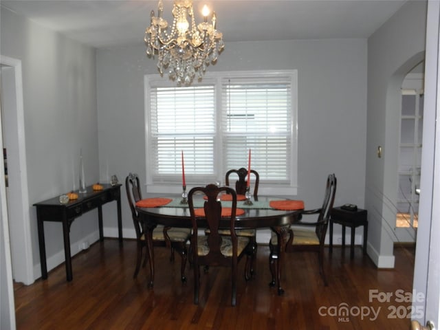 dining space featuring a chandelier, arched walkways, baseboards, and wood finished floors