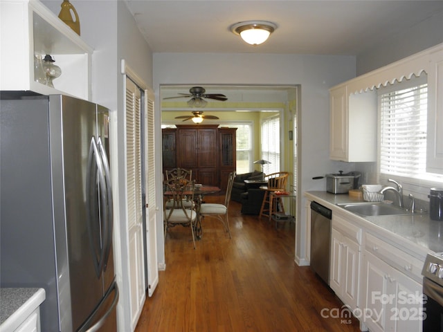 kitchen featuring dark wood finished floors, light countertops, appliances with stainless steel finishes, white cabinetry, and a sink