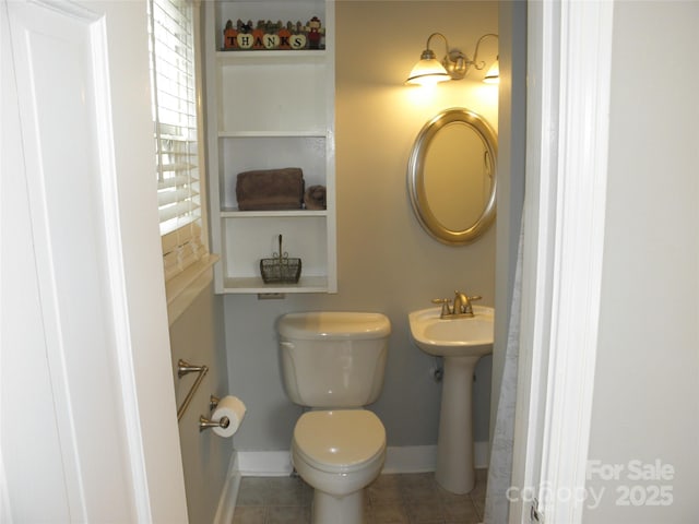 bathroom with toilet, baseboards, and a sink