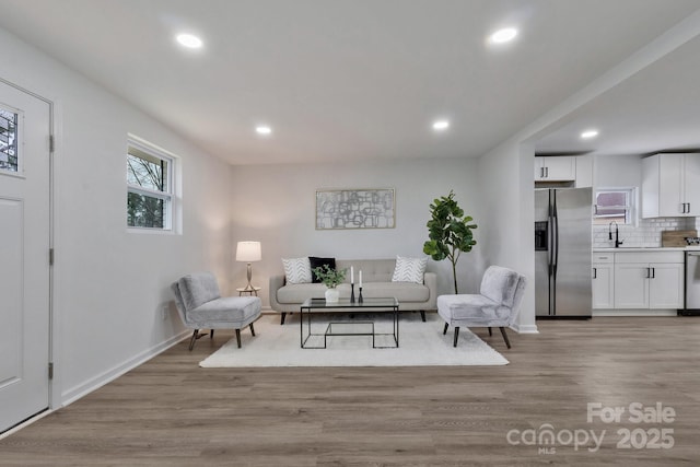 living room with light wood-style floors, recessed lighting, and baseboards