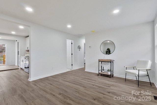 empty room with baseboards, wood finished floors, and recessed lighting