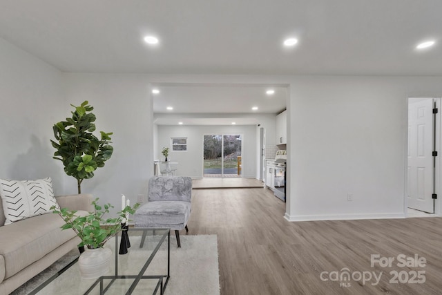 living area with baseboards, recessed lighting, and light wood-style floors