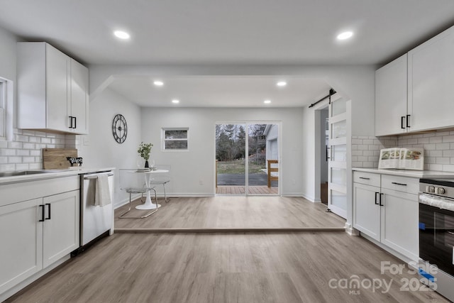 kitchen featuring stainless steel appliances, light countertops, a barn door, white cabinets, and light wood-type flooring