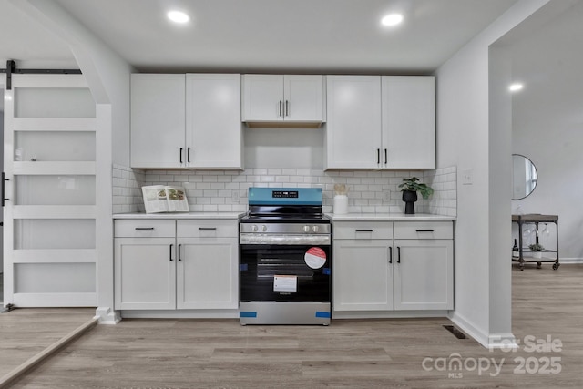 kitchen with white cabinets, light wood finished floors, electric range, and light countertops