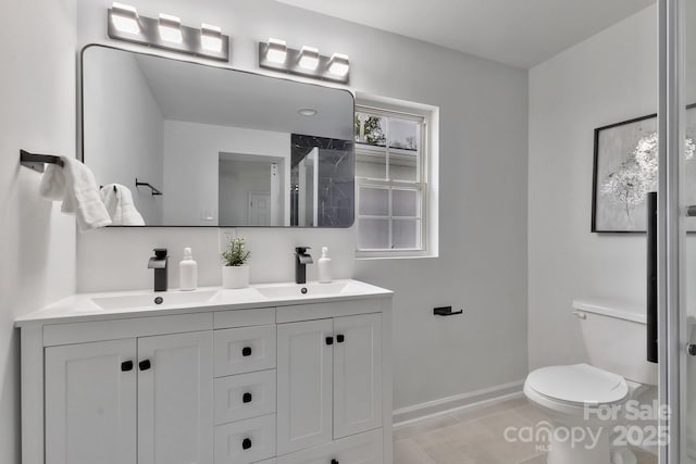 full bathroom with double vanity, a sink, toilet, and baseboards