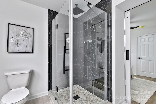 full bath featuring a marble finish shower, baseboards, and toilet