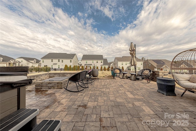 view of patio featuring fence, a fire pit, and a residential view