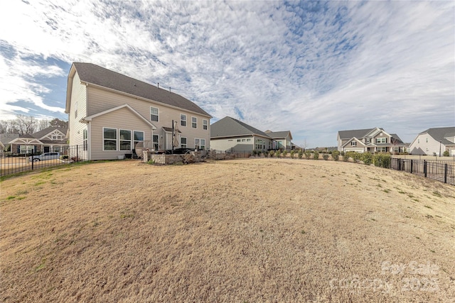 back of house featuring a residential view, a lawn, and fence