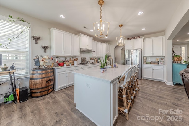 kitchen with white cabinetry, light countertops, wood finished floors, and stainless steel appliances