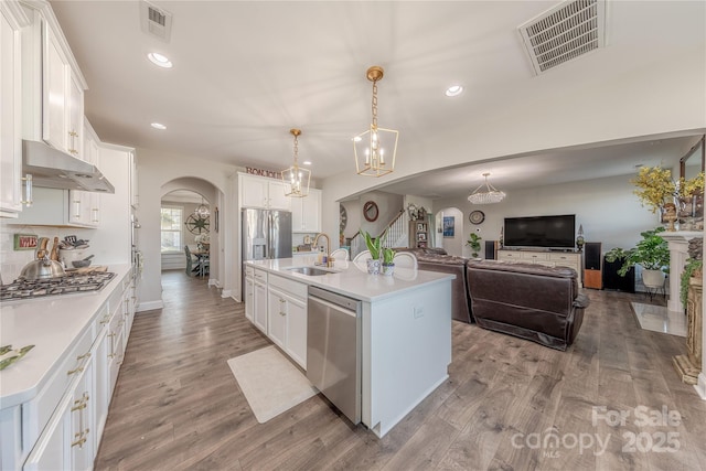 kitchen with visible vents, under cabinet range hood, appliances with stainless steel finishes, arched walkways, and a sink