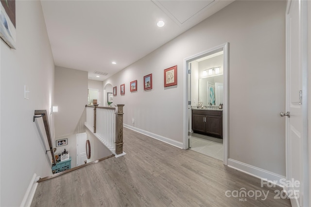 corridor featuring visible vents, an upstairs landing, wood finished floors, recessed lighting, and baseboards