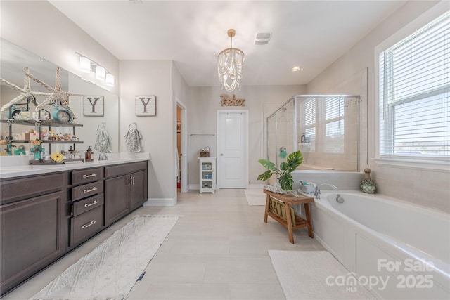 bathroom featuring baseboards, double vanity, a sink, a shower stall, and a garden tub