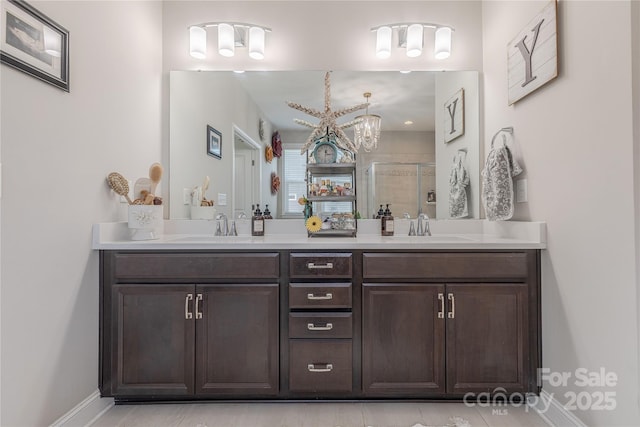 full bath featuring a sink, baseboards, double vanity, and a shower stall