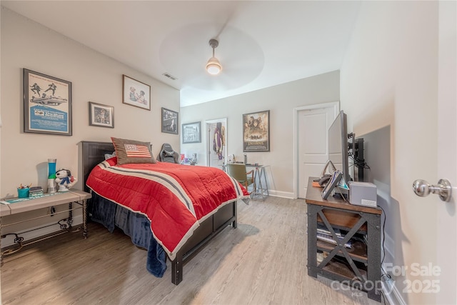 bedroom featuring visible vents, a ceiling fan, baseboards, and wood finished floors