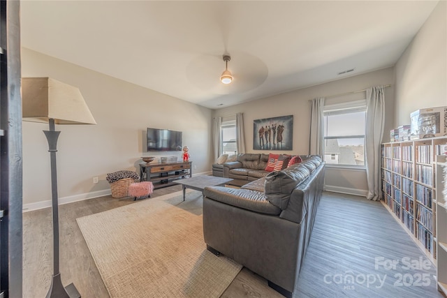 living room featuring visible vents, a ceiling fan, baseboards, and wood finished floors