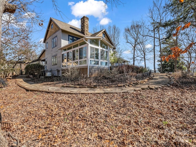 back of house featuring a sunroom and a chimney