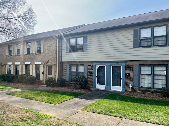 multi unit property with a front yard and brick siding