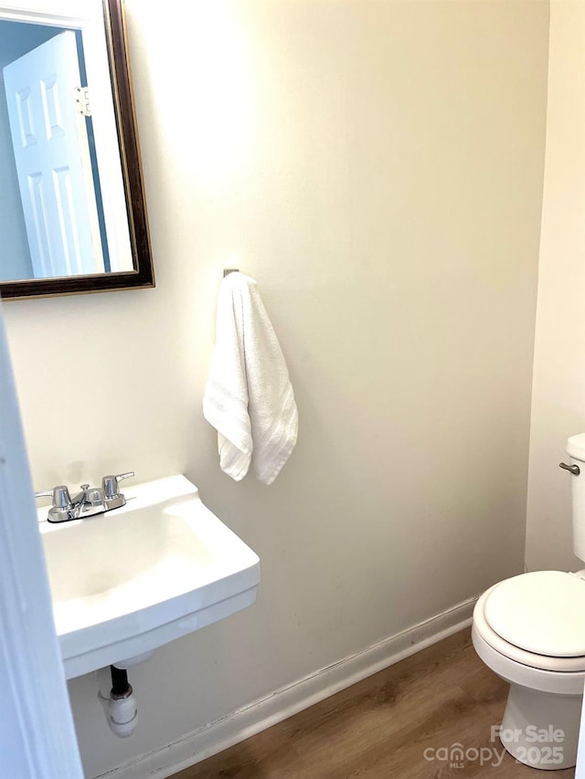 bathroom featuring a sink, toilet, baseboards, and wood finished floors