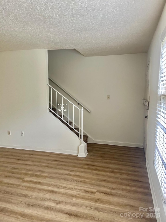 interior space with stairway, baseboards, a healthy amount of sunlight, and wood finished floors