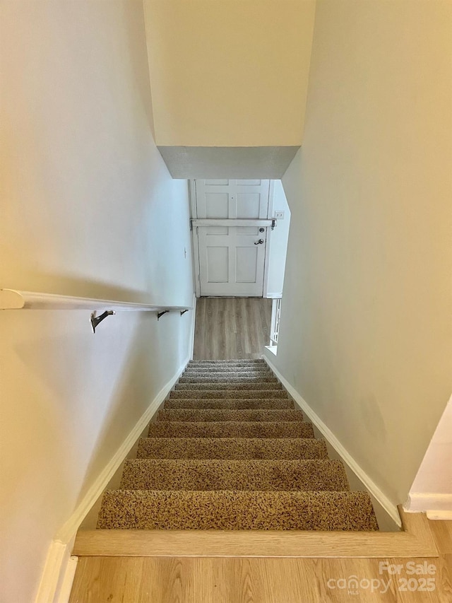 staircase featuring baseboards and wood finished floors