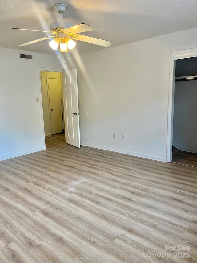 unfurnished bedroom featuring ceiling fan, a textured ceiling, baseboards, and light wood-type flooring