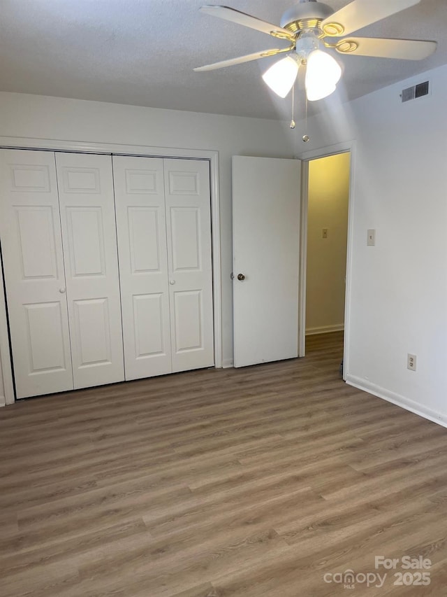 unfurnished bedroom featuring light wood finished floors, a closet, and visible vents