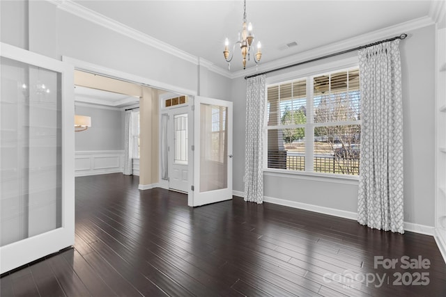 unfurnished room featuring crown molding, a notable chandelier, wood finished floors, and visible vents