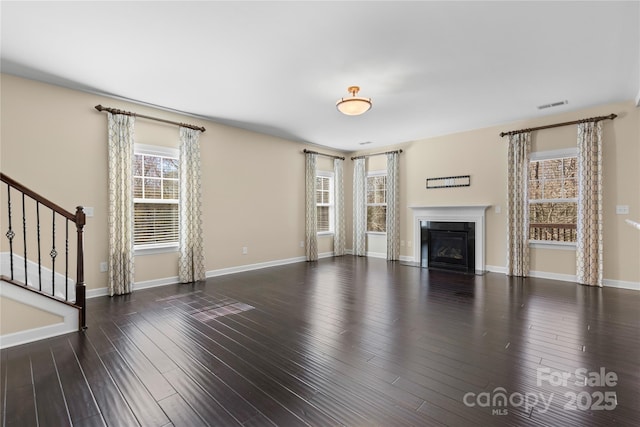 unfurnished living room with visible vents, baseboards, stairway, wood finished floors, and a glass covered fireplace