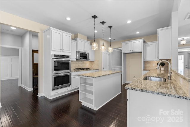 kitchen with a sink, open shelves, white cabinetry, and stainless steel appliances