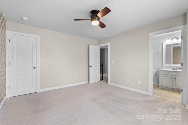 unfurnished bedroom featuring a sink, baseboards, ensuite bathroom, and light carpet
