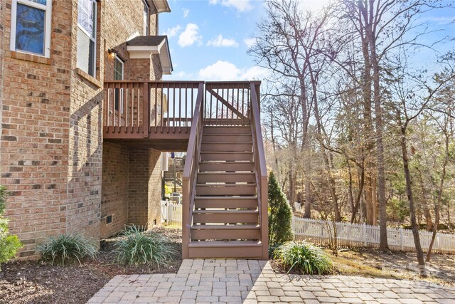 exterior space with brick siding, a wooden deck, and fence
