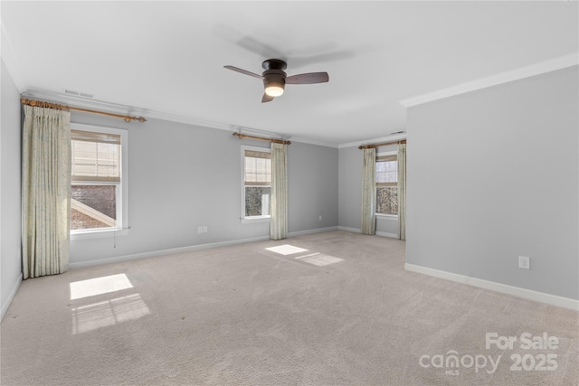 carpeted spare room featuring crown molding, baseboards, visible vents, and ceiling fan
