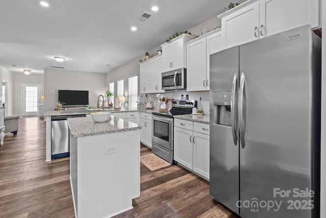 kitchen featuring open floor plan, dark wood finished floors, white cabinetry, appliances with stainless steel finishes, and a peninsula