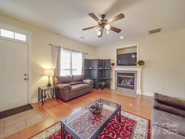 living room with visible vents, a fireplace, baseboards, and wood finished floors