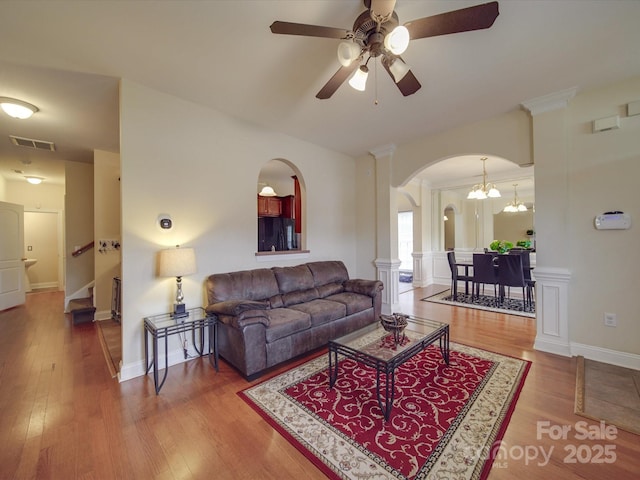 living room with visible vents, arched walkways, a ceiling fan, stairway, and wood finished floors