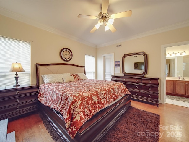 bedroom with wood finished floors, visible vents, and crown molding