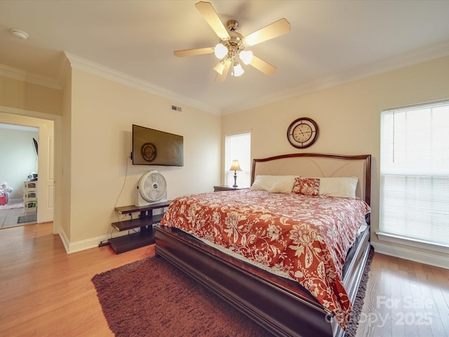 bedroom featuring light wood-style floors, multiple windows, ornamental molding, and baseboards