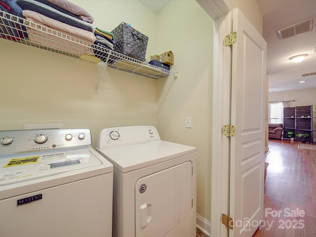 washroom featuring laundry area, wood finished floors, washing machine and clothes dryer, and visible vents