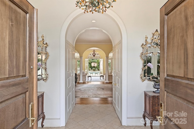 entryway featuring crown molding, arched walkways, and a chandelier