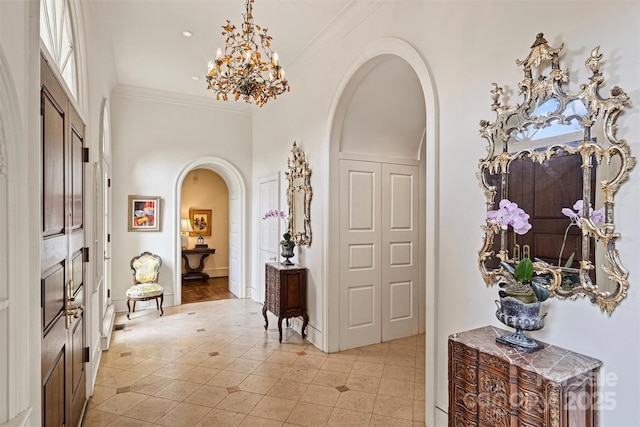 hallway with a notable chandelier, baseboards, arched walkways, and ornamental molding